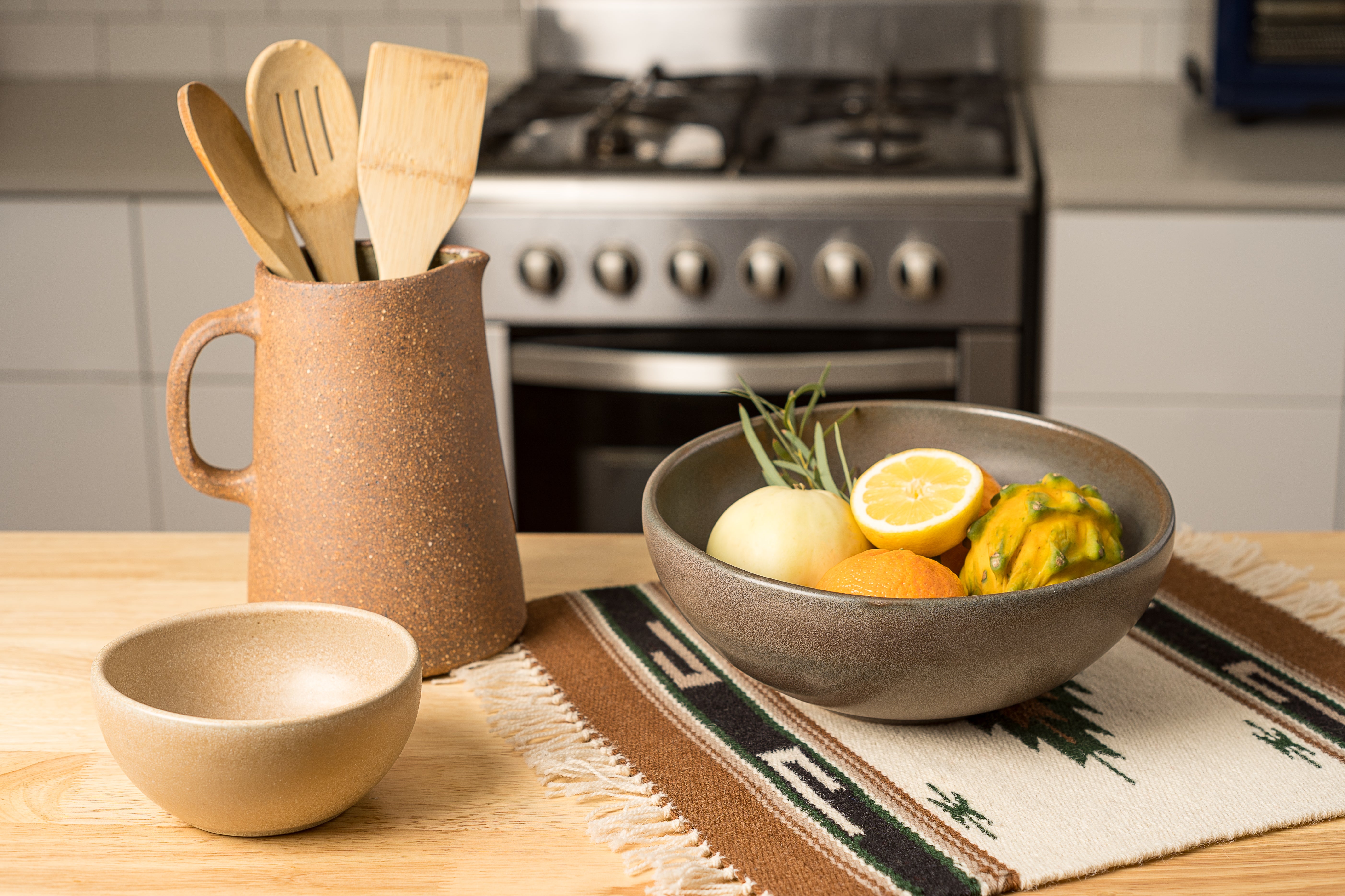 Kitchen counter with ceramic bowls and utensils, stove in the background